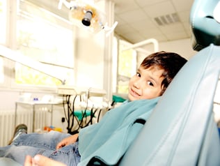 At dentists modern working place, cute kid sitting on chair and smiling