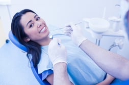 Dentist examining smiling female patient at dental clinic