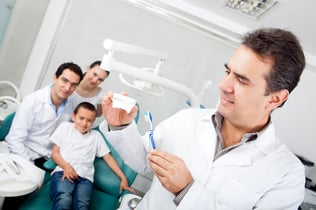 Dentist explaining how to brush teeth on a prosthesis