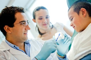 Dentist showing a boy how to brush his teeth