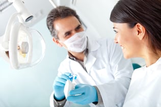 Dentist showing a woman how to brush her teeth on prosthesis-1