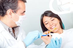 Dentist teaching a female patient how to brush teeth-1