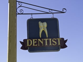 Dentists sign with gold tooth against a blue sky