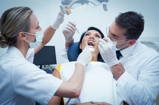 Male dentist with assistant examining womans teeth in the dentists chair-1