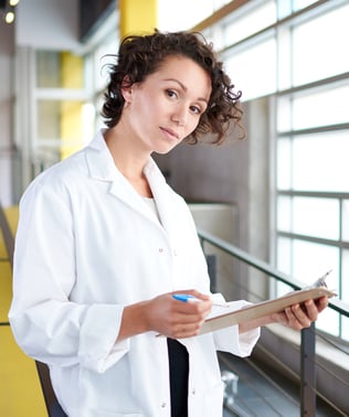 Portrait of a female doctor holding her patient chart in bright modern hospital