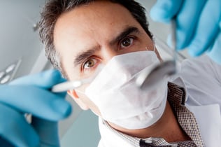 Professional male dentist holding instruments and wearing facemask-1