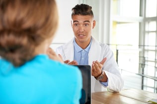 Team of doctor and nurse discussing a patient diagnosis sitting at the desk in bright modern office