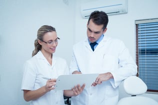 View of female and male dentists discussing reports