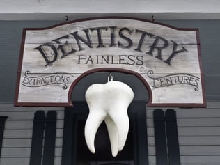 Vintage sign with giant tooth hanging in front of dentists office